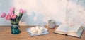 Easter eggs, book and pink tulips on table. Simple holiday image