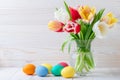 Easter eggs and a bouquet of tulips on a wooden table, floral still life. Holiday concept. Greeting card with copy space, empty Royalty Free Stock Photo