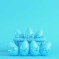 Easter eggs with bow in a wicker basket on bright blue background in pastel colors