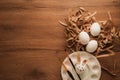 Easter, eggs on brown paper, paintbrush and painted egg like a rabbit face in color dish on wooden table Royalty Free Stock Photo