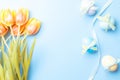 Easter eggs bunny. Colorful egg with tape ribbon  spring tulips  feathers on pastel blue background in Happy Easter decoration. Royalty Free Stock Photo