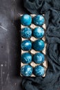 Easter eggs in cardboard packaging painted by hand in blue color