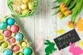 Easter eggs in a cardboard tray on a light wooden background, top view, tulips