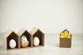 Easter eggs in decorative birdhouses with little yellow chickens near by on a white backround