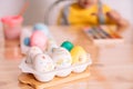 Easter eggs of different colors and in stickers in a white tray on a wooden table