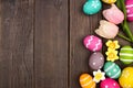 Easter eggs and flower decoration side border against a dark rustic wood background Royalty Free Stock Photo