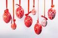Easter eggs with folk Ukrainian pattern hang on red ribbons from top on white background. Ukrainian traditional eggs Royalty Free Stock Photo