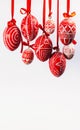 Easter eggs with folk Ukrainian pattern hang on red ribbons from top on white vertical background. Ukrainian traditional eggs Royalty Free Stock Photo