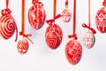 Easter eggs with folk Ukrainian pattern hang on red ribbons on white background Royalty Free Stock Photo