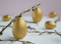 Easter. Easter eggs of gold and natural color with willow branches on a light background