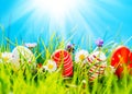 Easter eggs in green grass with flowers, blue sky and sun Royalty Free Stock Photo