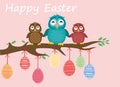 Easter eggs hang on ribbons. Lovely owls are sitting on a tree