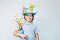 Easter eggs hunt tradition. Smiling boy kid in Easter hat holds easter tree in pot and chocolate egg in other hand on