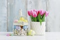 Easter eggs inside a vintage bird cage and bouquet of pink tulips in ceramic vase Royalty Free Stock Photo