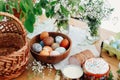 Easter eggs natural dyed, easter bread cake, ham, butter, green branches  and flowers on rustic wooden table with wicker basket Royalty Free Stock Photo