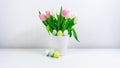 Easter eggs near a bouquet of spring natural fresh tulips flowers. Easter greeting card. White background Royalty Free Stock Photo