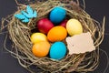 Easter eggs in the nest and blank handmade paper sheet. Blank gretting card for Easter holidays. On black background Royalty Free Stock Photo