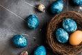 Easter eggs in nest painted by hand in blue color on dark background Royalty Free Stock Photo