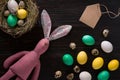 Easter eggs in nest and pink rabbit on a black background Royalty Free Stock Photo
