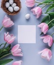 Easter eggs in nest, pink tulips flowers and sheet of paper over light blue background. Greeting card for Happy Easter. Flat lay, Royalty Free Stock Photo