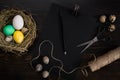 Easter eggs in nest, scissors and thread on a black background Royalty Free Stock Photo