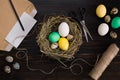 Easter eggs in nest, scissors and thread on a black background Royalty Free Stock Photo