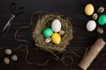 Easter eggs in nest, scissors and thread on a black background Royalty Free Stock Photo