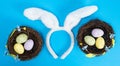 Easter eggs in nests and rabbit ears on a blue background, top view Royalty Free Stock Photo