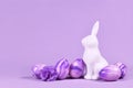 Easter eggs next to bunny figure on violet background Royalty Free Stock Photo