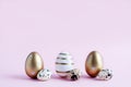 Easter eggs painted with gold paint in different patterns are on a pink background and next to three quail eggs. Easter. Place for Royalty Free Stock Photo