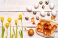 Easter eggs painted with natural dye, onion husk on a white wooden background and yellow spring flowers Narcis