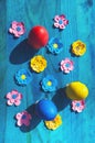 Easter eggs and paper flowers on blue wooden background