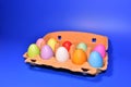 Easter eggs in a paperboard. Multi-colored eggs in egg carton on blue background. Easter is a Christian holiday that celebrates Royalty Free Stock Photo