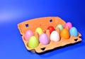 Easter eggs in a paperboard. Multi-colored eggs in egg carton on blue background. Easter is a Christian holiday that celebrates Royalty Free Stock Photo