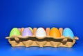 Easter eggs in a paperboard. Multi-colored eggs in egg carton on blue background. Easter is a Christian holiday that celebrates Royalty Free Stock Photo