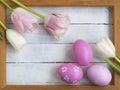 Easter eggs, photo frame, tulips on a white wooden background