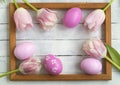 Easter eggs, photo frame, tulips on a white wooden background