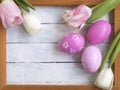 Easter eggs, photo frame, tulips on a white wooden background
