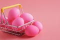 Easter eggs on pink background and shopping cart with eggs closeup Royalty Free Stock Photo