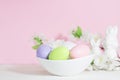 Easter Eggs, Pink, Green And Lilac, In A White Plate, Near Rabbits And Flowers On A Pink Background. Pastel Shades