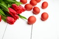 Easter Eggs and red flowers on white wooden table. Painted chicken eggs and red tulip Royalty Free Stock Photo