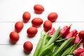 Easter Eggs and red flowers on white wooden table. Painted chicken eggs and red tulip Royalty Free Stock Photo