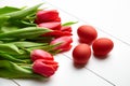 Easter Eggs and red flowers on white wooden table. Painted chicken eggs and red tulip Royalty Free Stock Photo