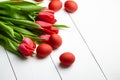 Easter Eggs and red flowers on white wooden table. Painted chicken eggs and red tulip Royalty Free Stock Photo