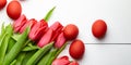 Easter Eggs and red flowers on white wooden table, top view. Painted chicken eggs and red tulip Royalty Free Stock Photo