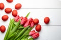 Easter Eggs and red flowers on white wooden table, top view. Painted chicken eggs and red tulip Royalty Free Stock Photo
