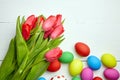 Easter Eggs and red tulip flowers on white wooden table Royalty Free Stock Photo