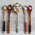 Easter eggs - speckled and sugar coated on wooden and silver spoons on white rustic wooden table, top view.