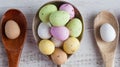 Easter eggs - speckled and sugar coated on wooden and silver spoons on white rustic wooden table, top view extreme closeup.