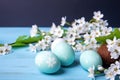 Easter eggs and sprig flowers on blue wooden background. Generative Ai